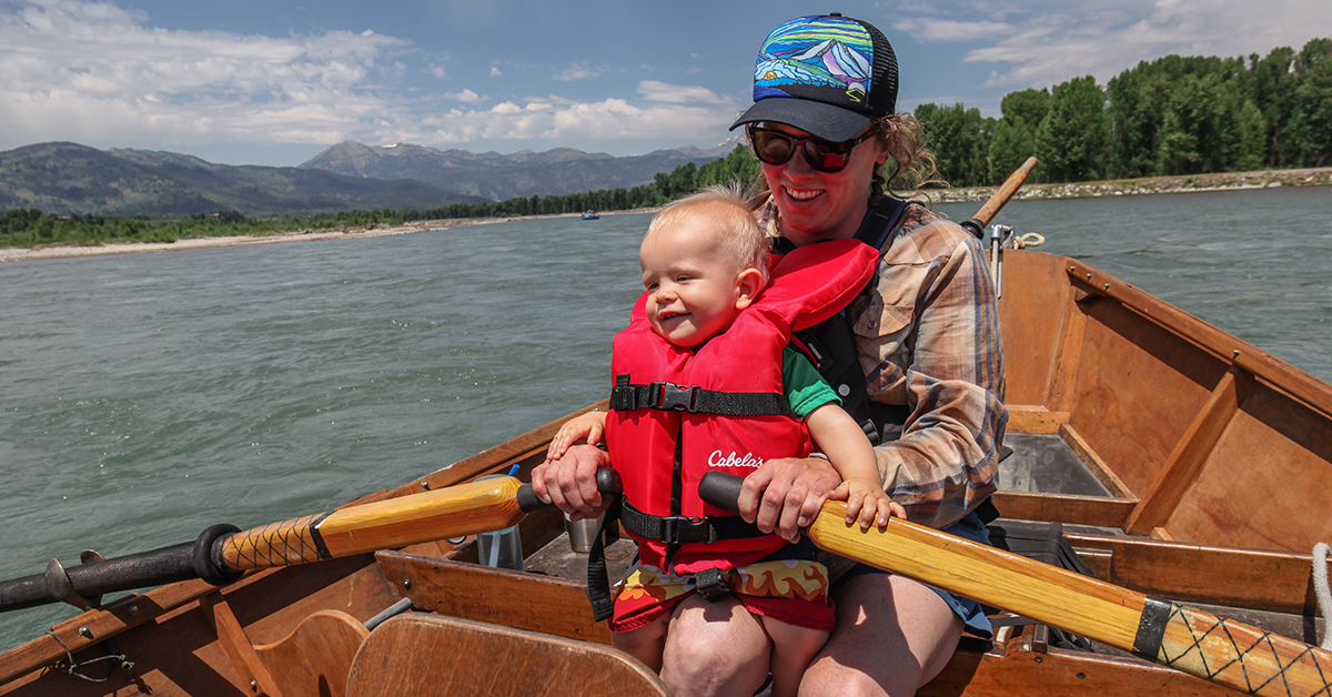 A River Guide Shows A Toddler How To Use The Oars In A Vintage Wooden Boat On A Luxury Float On The Snake River In Jackson Hole